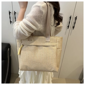 Detail of woven tote bag with front zipper pocket and yellow braided rope puller