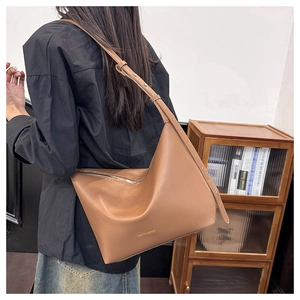 Close-up of the soft brown leather tote bag with subtle golden lettering detail