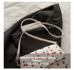 Detail view of the adjustable white shoulder strap with cherry print and metal buckle