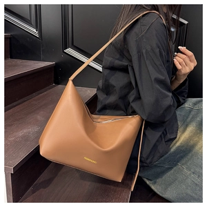 Close-up of brown leather hobo bag with gold Fashion & Bags lettering and wide strap