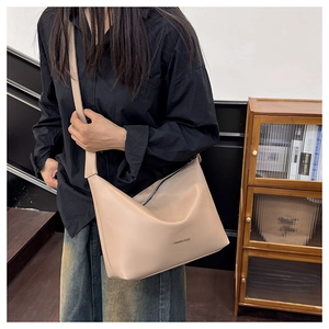 Détail d'un sac hobo en similicuir beige avec bandoulière large et logo tendance
