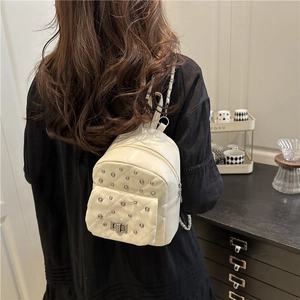 White quilted mini backpack with diamond stitching and metal chain straps worn by model