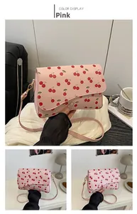 Detailed macro view of pink cherry print PU leather bag with golden hardware buckle