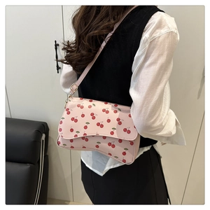 Close-up of a pink shoulder bag featuring a cute red cherry print and adjustable strap