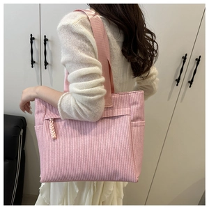 Detailed view of pink woven tote bag with side pocket and braided zipper detail