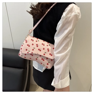 Detail of light pink shoulder bag with cherry print and adjustable strap on model
