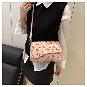 Detail of light pink crescent bag with red cherry prints and adjustable golden hardware buckle