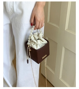 Detailed shot of dark brown bucket bag with large pearl handle and drawstring closure