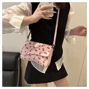 Detail of pink cherry print crossbody bag with curved bottom and thin shoulder strap
