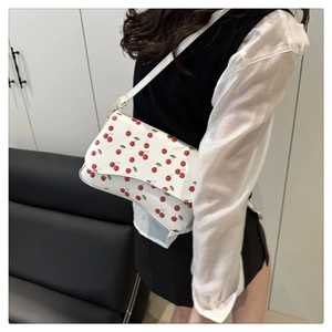 Detail of sweet cherry print on a white crescent crossbody bag with flap closure
