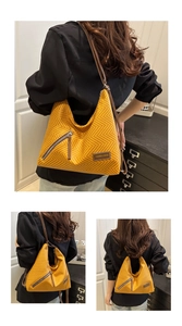 Detail of ginger yellow woven tote bag showing herringbone texture and leather label