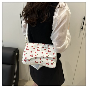 Close-up of white crescent bag with cherry print on a model in a minimal interior