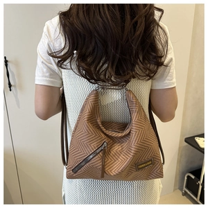 Detail view of woven brown multi-functional backpack with diagonal zipper pocket design