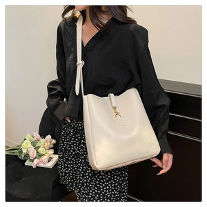 Detail of cream leather bucket bag with gold clasp shown on model with black shirt