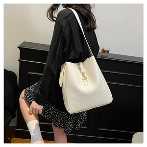 Detail view of cream white leather bucket bag with elegant gold metal hook buckle on strap