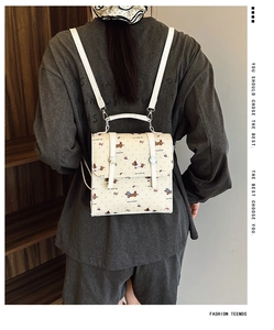 Détail d'un mini sac à dos avec imprimés teckel et cerise et bretelles en cuir blanc