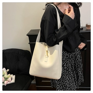 Detail of cream leather tote bag with elegant gold clasp and wide strap on model