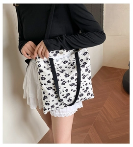 Close-up of white floral canvas tote bag with black cherry blossom patterns and magnetic clasp