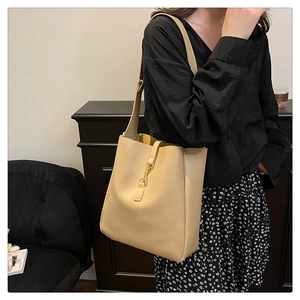Detail of soft beige leather tote bag featuring a metallic gold piston buckle closure