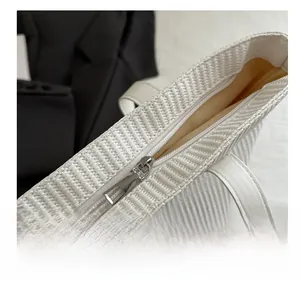 Detail of smooth metal zipper closure on white woven textured commuter tote bag