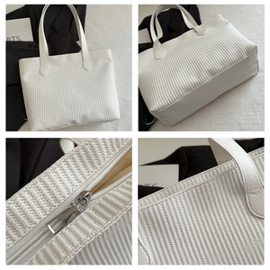 Detail view of large white textured tote bag featuring silver zipper and woven pattern