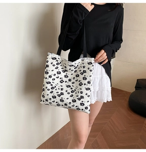 Close-up of floral canvas tote bag featuring black flower prints and white lace trim