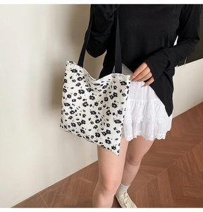 Detail of floral canvas tote bag featuring black flower patterns and lace trim edges