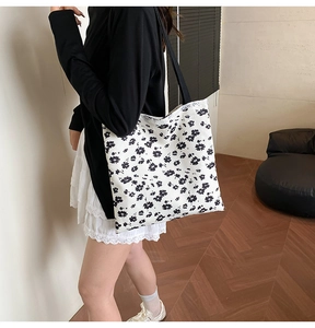 Detail of floral canvas tote bag featuring white lace trim and black shoulder straps
