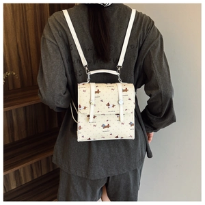 Detail of cream-colored backpack with dachshund and cherry patterns and leather straps