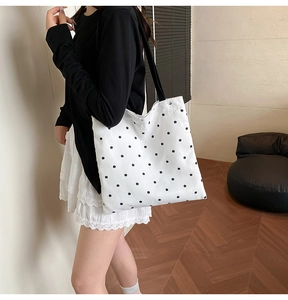 Close-up of white canvas tote bag featuring black floral print and lace edge detailing