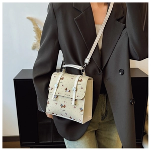 Detail of cream crossbody bag featuring dachshund prints on a stylish model outfit