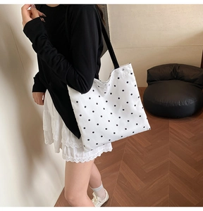 Lace-trimmed canvas tote bag with black floral print shown worn by a model