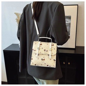 Back view of a mini beige backpack with cute dog patterns on a grey blazer model