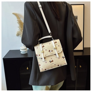 Detail of cream crossbody bag featuring cartoon dachshund prints and white shoulder strap