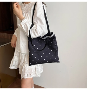 Detail of black polka dot canvas tote bag with floral prints and lace trim decoration