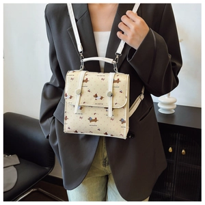 Detail of beige dachshund print mini bag with adjustable white strap on model