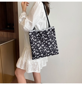Detail of black floral canvas tote bag featuring white lace trim and daisy pattern