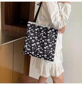 Detail of floral tote bag with delicate lace trim and black shoulder strap on a model