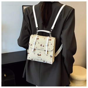 Detail of a mini cream backpack featuring cartoon dachshund prints and metal clasp closure