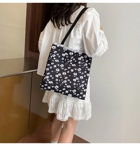 Detail of black floral canvas tote with white daisy print and delicate lace trimming