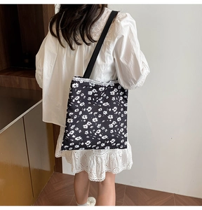Detailed side view of black polka dot canvas tote bag with elegant white lace trim detail