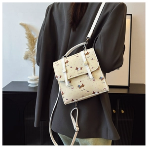 Close-up of a mini cartoon dachshund print crossbody bag on a model wearing a dark blazer