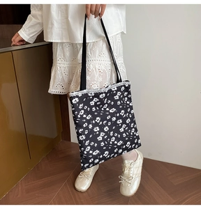 Detail of floral canvas tote bag featuring white lace trim and black shoulder straps