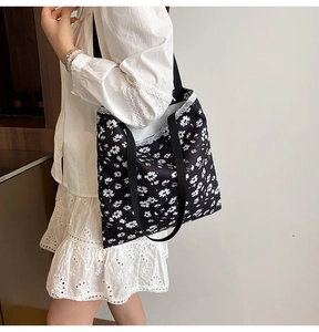Detail of black floral canvas tote bag with white lace trim and floral pattern