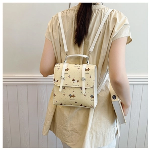 Detail view of mini yellow backpack with dachshund print on a model's back