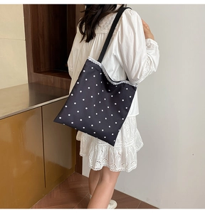 Detail of floral canvas tote bag with white lace trim and shoulder strap on model
