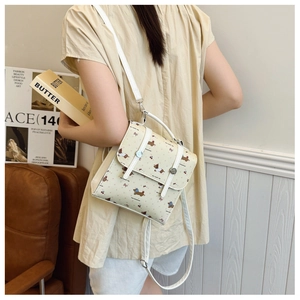 Close-up of cream crossbody bag featuring cute cartoon dogs and pink bow prints