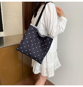 Close-up of floral canvas shoulder bag with white lace trim and black strap detail