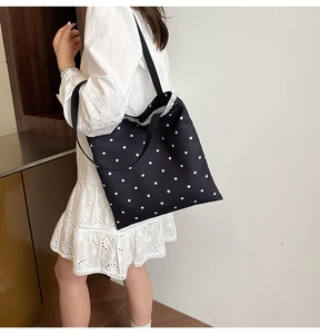Detail of floral canvas tote bag with white lace trim and black wide shoulder strap