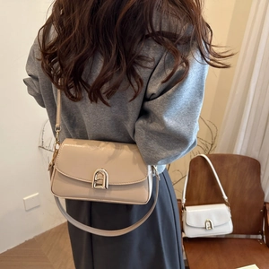 Sac à bandoulière beige élégant avec boucle en arche porté par un mannequin chic